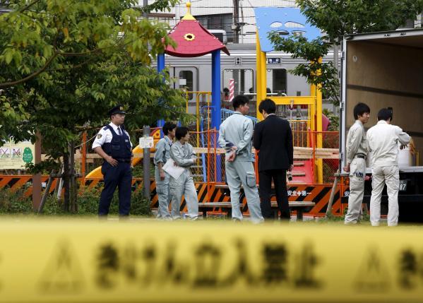 Workers of Tokyo's Toshima ward office and police officers are seen in front of playground equipment where high levels of radiation were detected at park in Toshima ward, Tokyo